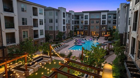 an aerial view of an apartment complex with a swimming pool at night